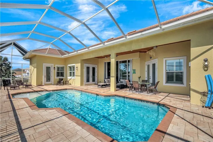 Pool with french doors, glass enclosure, a patio, and ceiling fan
