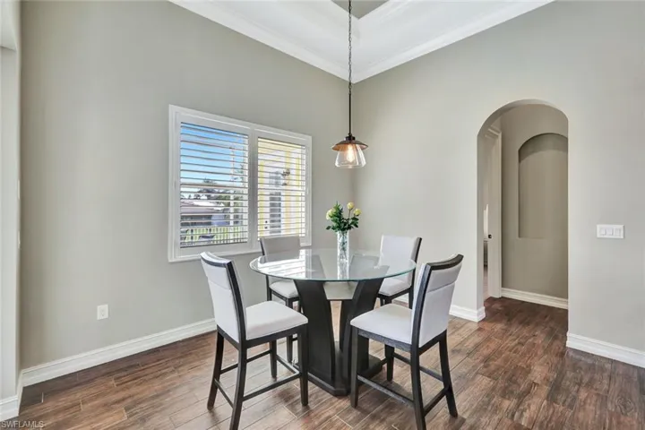 Dining room featuring arched walkways, ornamental molding, dark wood finished floors, and baseboards