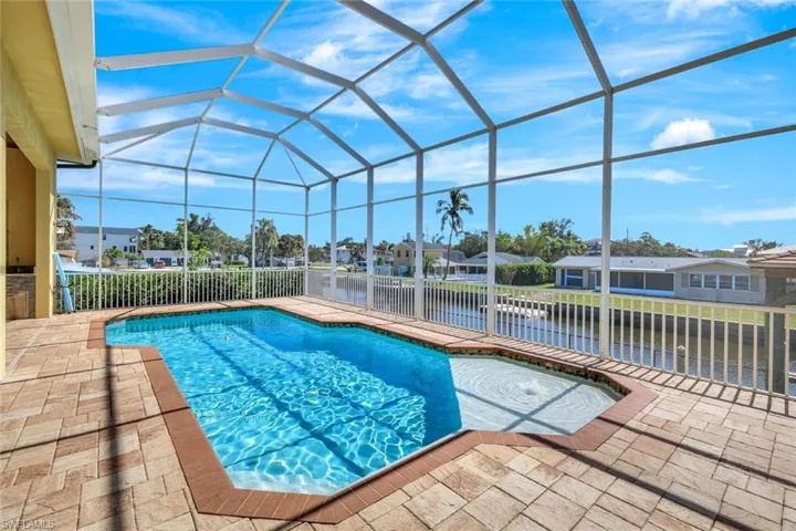 Outdoor pool featuring a residential view, glass enclosure, a water view, and a patio