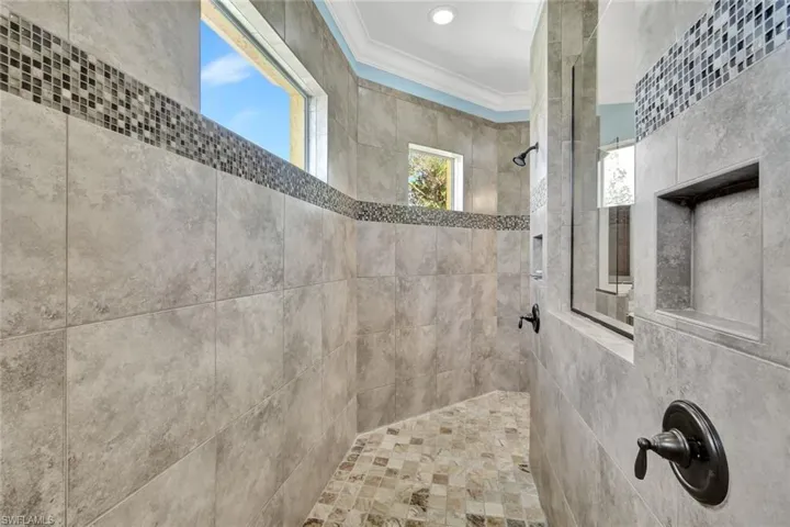 Bathroom featuring ornamental molding and a tile shower