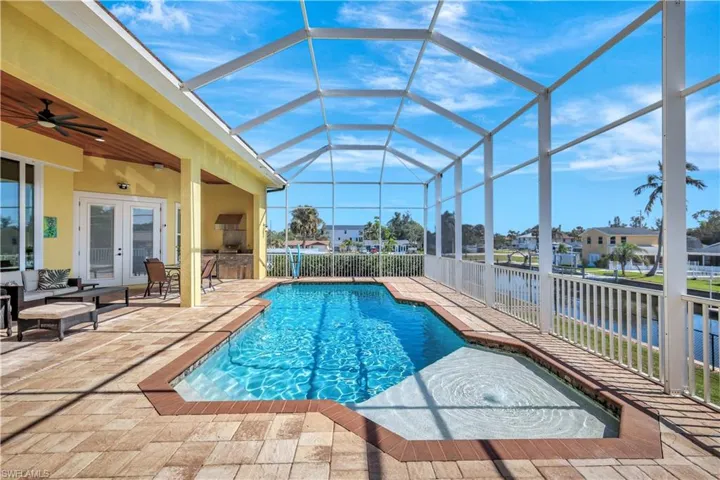 View of swimming pool featuring a patio area, glass enclosure, french doors, and a water view