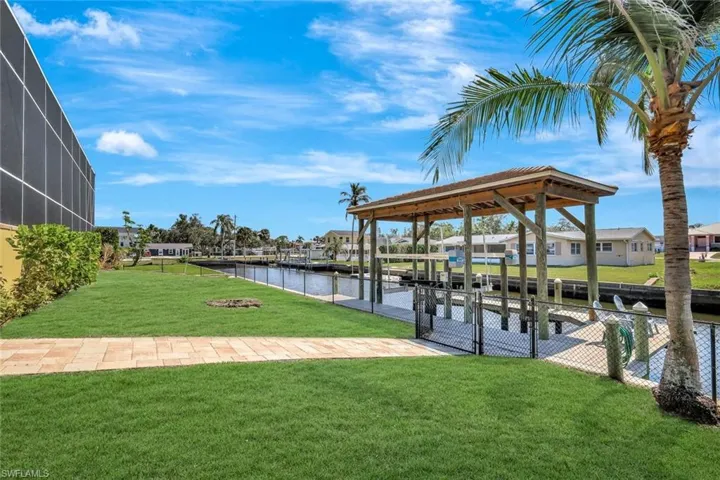 View of dock with a water view, glass enclosure, and a yard