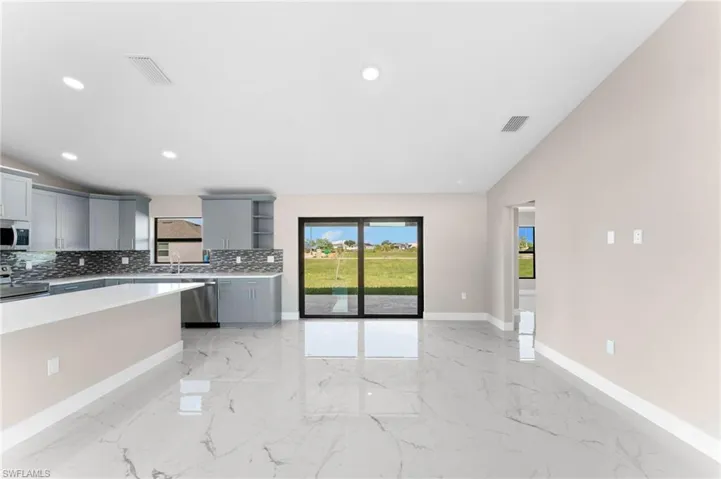Kitchen with light tile patterned flooring, tasteful backsplash, stainless steel appliances, and gray cabinetry