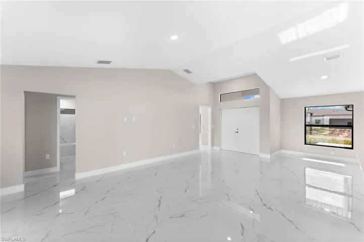Unfurnished living room featuring tile patterned floors and vaulted ceiling
