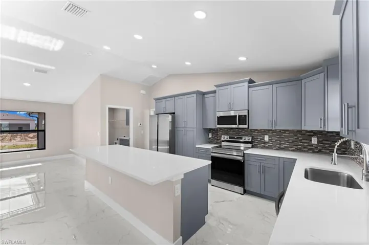 Kitchen featuring tasteful backsplash, sink, appliances with stainless steel finishes, and light tile patterned floors