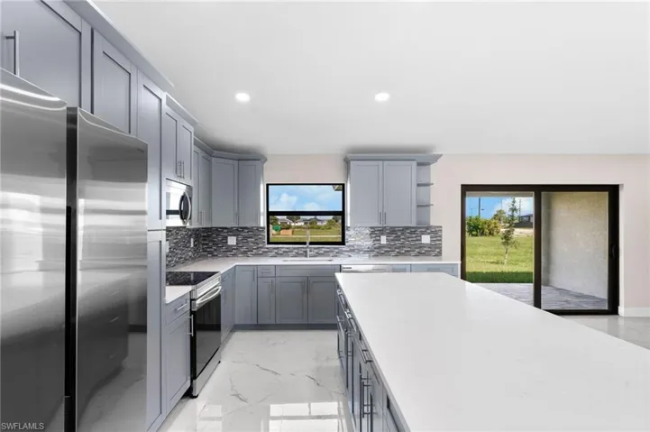 Kitchen featuring backsplash, a healthy amount of sunlight, appliances with stainless steel finishes, and gray cabinetry