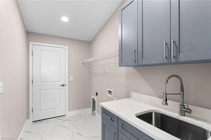 Laundry room featuring sink, electric dryer hookup, cabinets, hookup for a washing machine, and light tile patterned floors