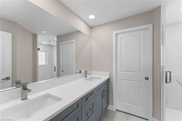 Bathroom with tile patterned floors, a shower with door, and double sink vanity