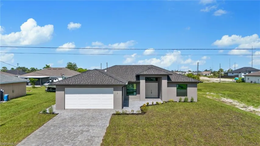 View of front facade featuring a garage and a front lawn