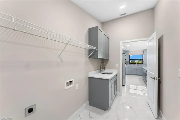 Laundry area with hookup for a washing machine, sink, cabinets, light tile patterned floors, and electric dryer hookup