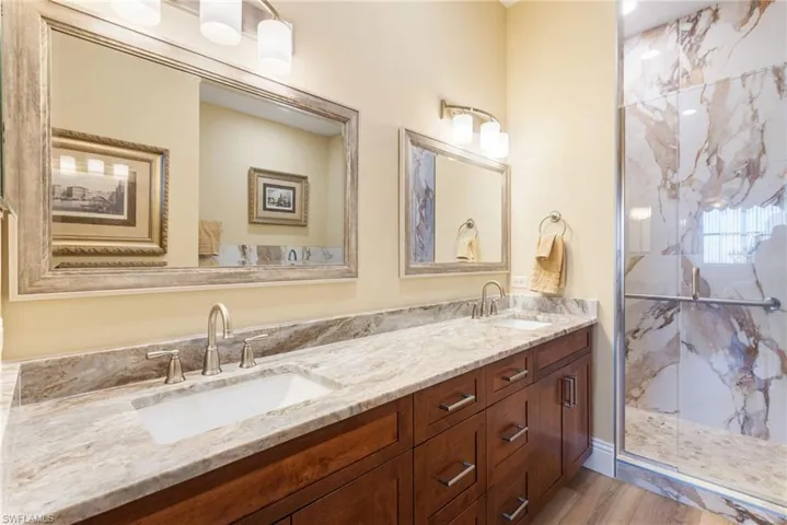 completely remodeled primary bathroom offers floor to ceiling tile, walk in shower and dual comfort height vanities.