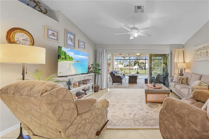 Living area featuring vaulted ceiling, tile patterned flooring, a ceiling fan, and a sunroom