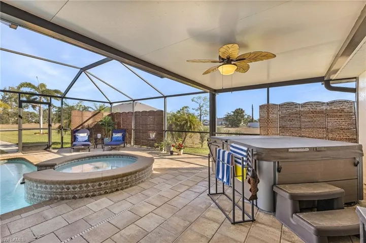 View of patio / terrace with a lanai, a sunroom, ceiling fan, and a pool with connected hot tub
