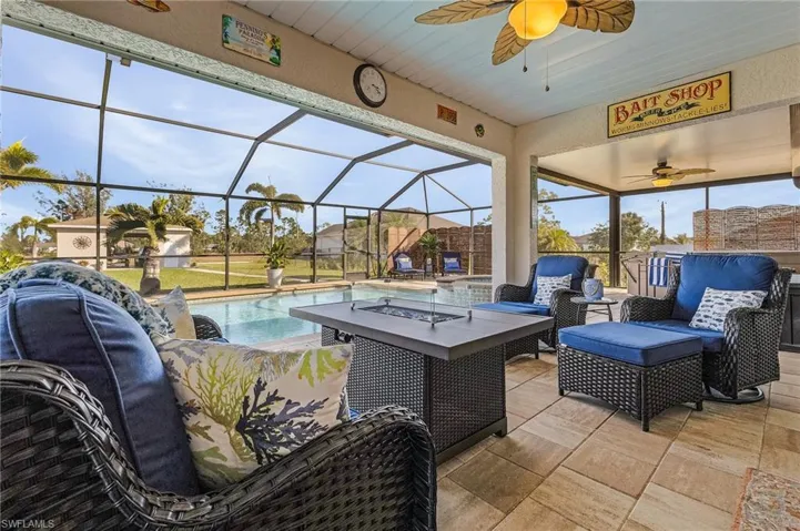 View of patio featuring ceiling fan, a lanai, a sunroom, an outdoor living space with a fire pit, and an outdoor pool