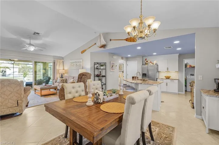 Dining room with lofted ceiling, light tile patterned flooring, a chandelier, ceiling fan, and washer / dryer