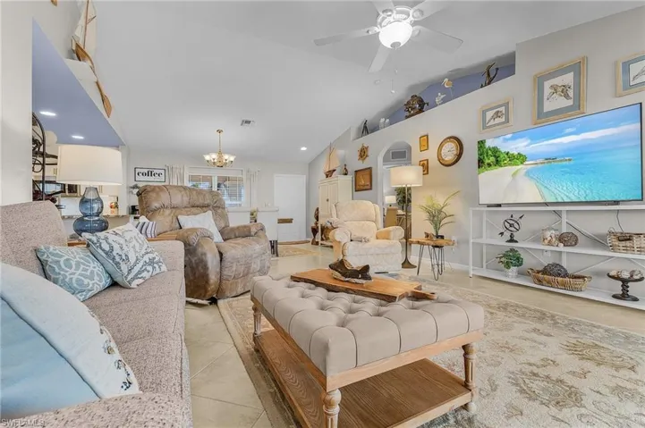 Tiled living room featuring lofted ceiling, a chandelier, a ceiling fan, and recessed lighting