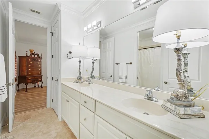Double vanity with integrated sinks and polished chrome faucets, featuring a spacious countertop and extensive under-sink cabinetry
