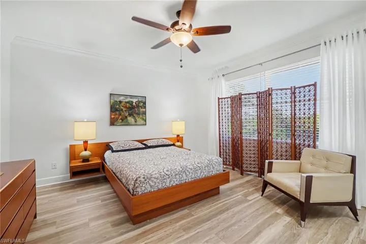 Spacious room featuring light wood-finish flooring, crown molding, and a ceiling fan with integrated lighting