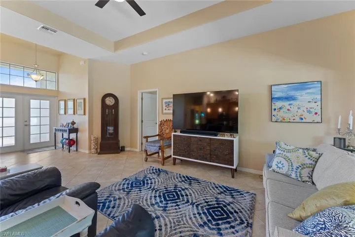 Tiled living room with towering ceiling and French doors