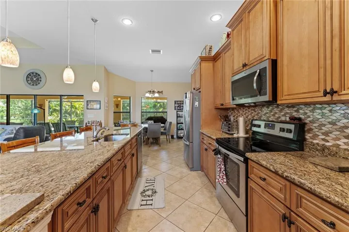 Kitchen with decorative backsplash, decorative light fixtures, appliances with stainless steel finishes, and a wealth of natural light