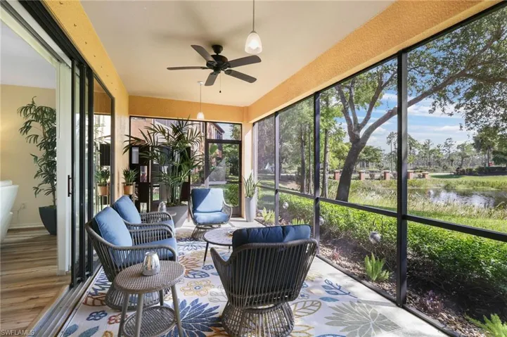 Sunroom / solarium with a ceiling fan and a water view