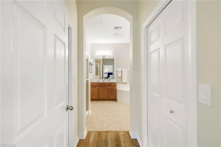 Corridor with arched walkways and light wood-style floors