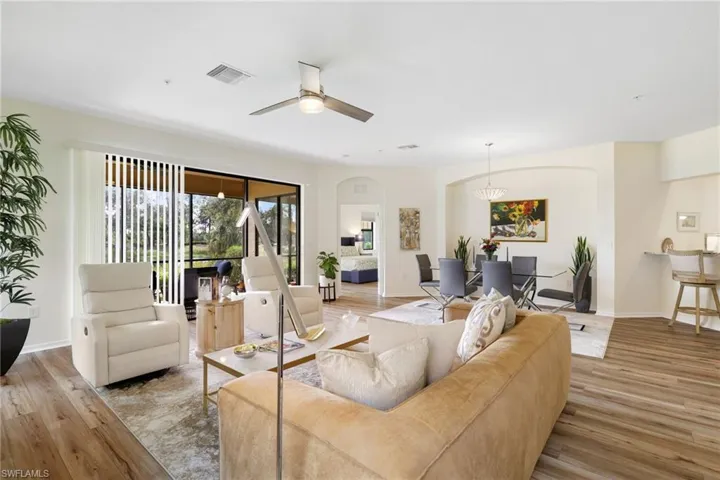 Living room featuring light wood-style floors, a ceiling fan, and arched walkways