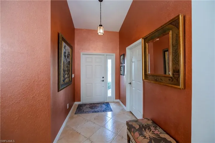 Foyer featuring baseboards, a textured wall, and a high ceiling