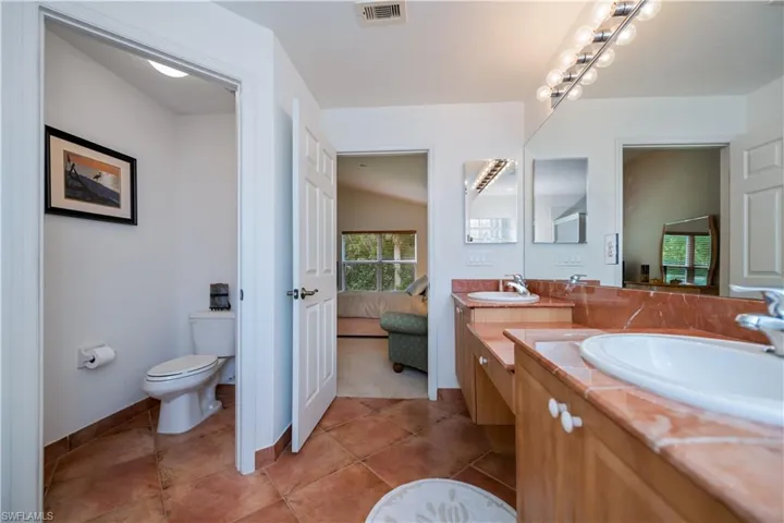 Full bath featuring toilet, a sink, visible vents, and double vanity