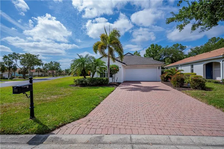 View of front facade with decorative driveway, a tiled roof, an attached garage, a front yard, and stucco siding