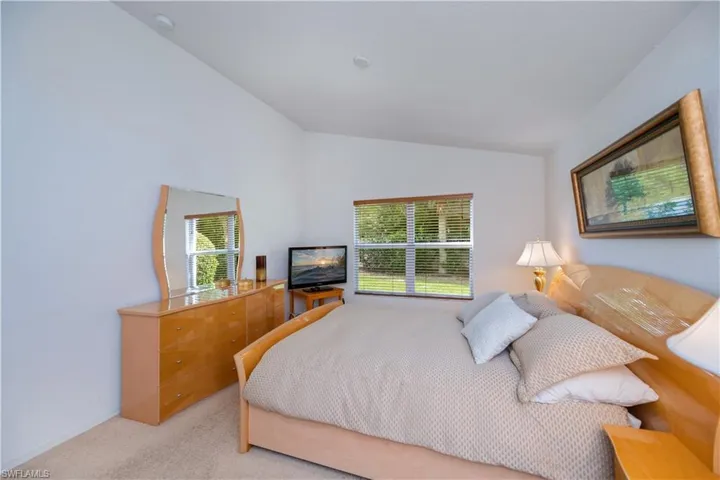 Bedroom featuring light carpet and vaulted ceiling