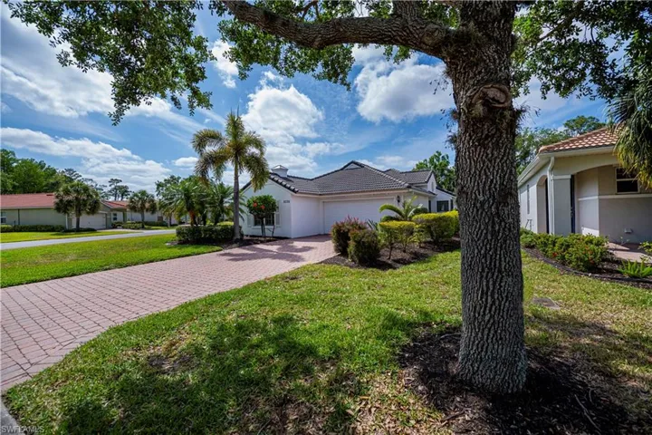 View of front of property with a tiled roof, a front lawn, stucco siding, driveway, and a garage