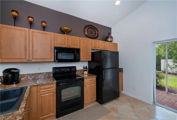 Kitchen with baseboards, a sink, black appliances, and high vaulted ceiling