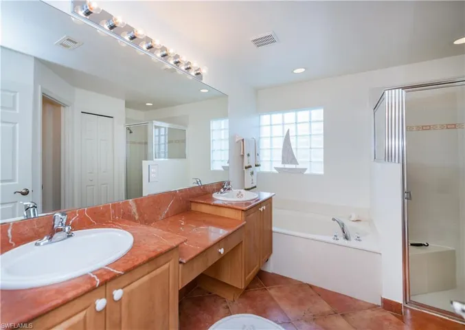 Full bathroom featuring a stall shower, visible vents, tile patterned flooring, a garden tub, and vanity