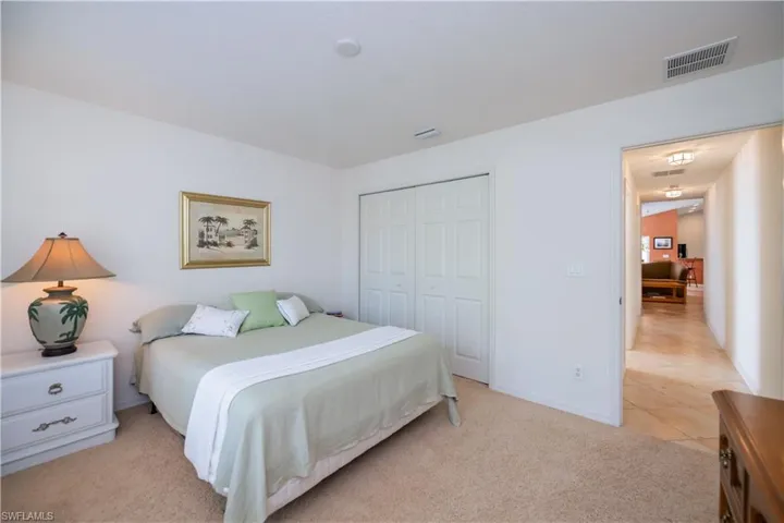 Bedroom featuring baseboards, light carpet, visible vents, and a closet