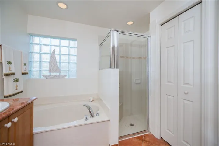 Bathroom with tile patterned floors, vanity, a bath, a closet, and a stall shower