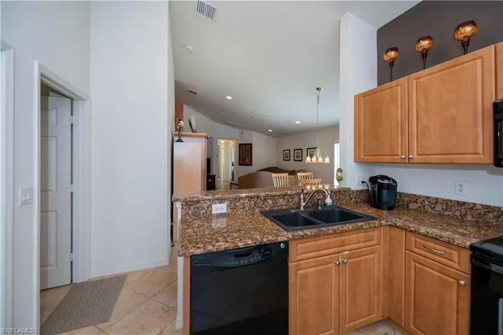 Kitchen featuring vaulted ceiling, a sink, black appliances, a peninsula, and visible vents