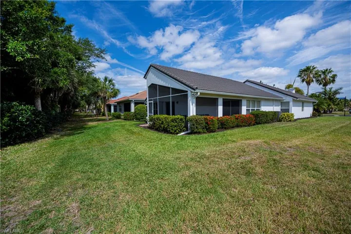 View of side of property featuring a lawn, a tile roof, a sunroom, and stucco siding