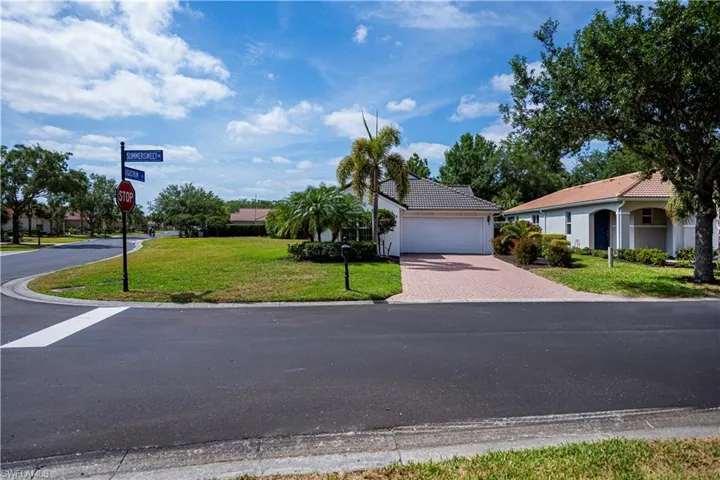 View of front of home with an attached garage, decorative driveway, a tiled roof, and a front yard