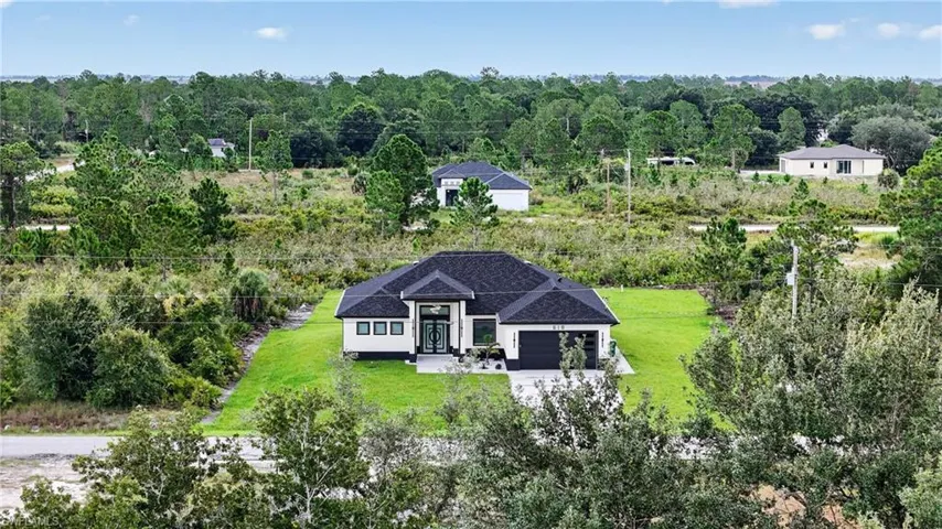 Contemporary single-story residence featuring a dark shingle roof, light-toned exterior, and a two-car garage