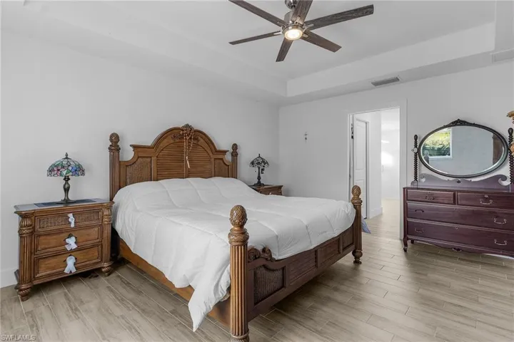 Bedroom featuring a tray ceiling, ceiling fan, and light hardwood / wood-style floors