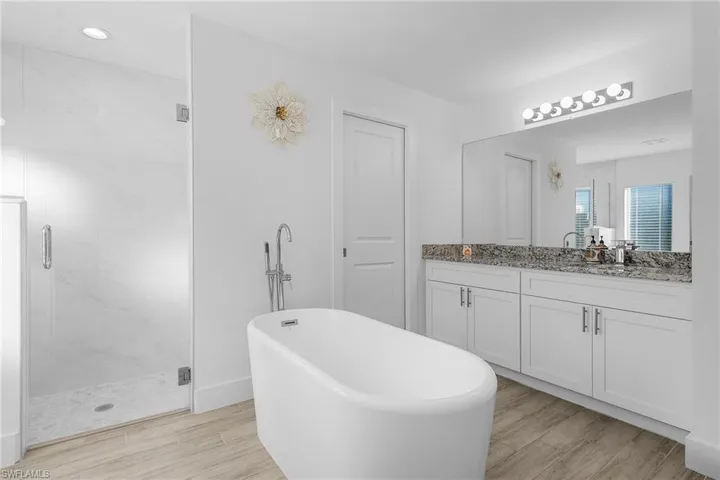 Bathroom with vanity, separate shower and tub, and wood-type flooring