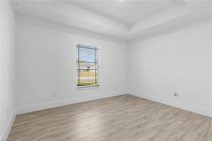 Bedroom featuring a raised ceiling and light wood-type flooring