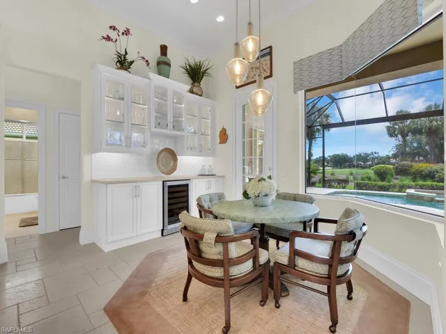 Dining room with wine cooler, stone tile flooring, a bar, and recessed lighting