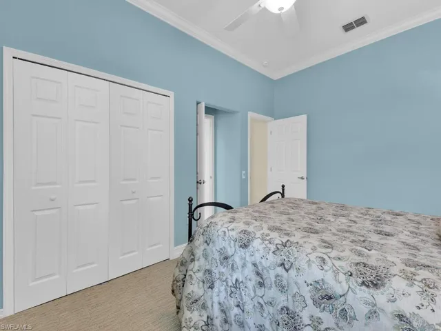 Carpeted bedroom with ornamental molding, a closet, and a ceiling fan