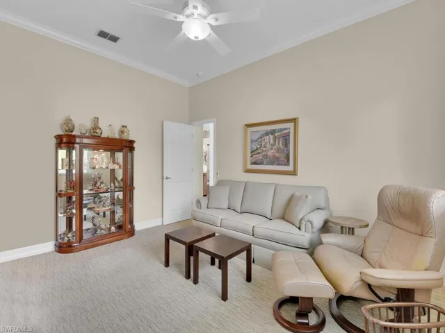 Carpeted living area with ceiling fan and ornamental molding