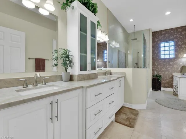 Full bath featuring wallpapered walls, double vanity, a walk in shower, and recessed lighting
