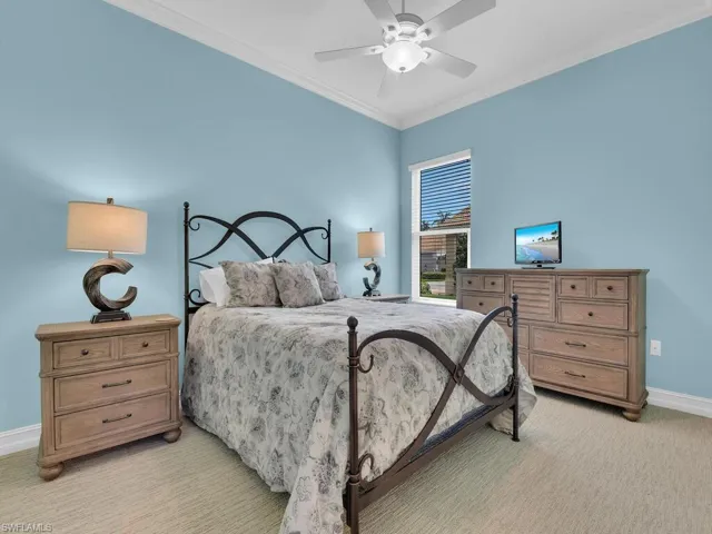 Bedroom featuring light colored carpet, ornamental molding, and ceiling fan