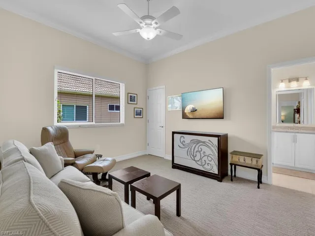 Living area with ceiling fan, light colored carpet, and ornamental molding