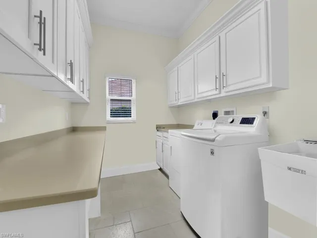 Washroom featuring cabinet space, washer and clothes dryer, and crown molding